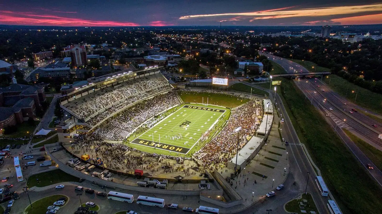 The Hornets' stadium lit up at sunset with a full crowd