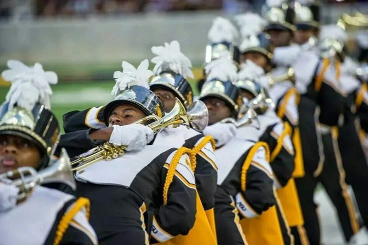 A row of trumpet players with white plumes plays in formation